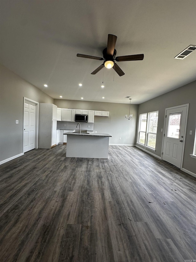 kitchen featuring open floor plan, stainless steel microwave, visible vents, and white cabinets