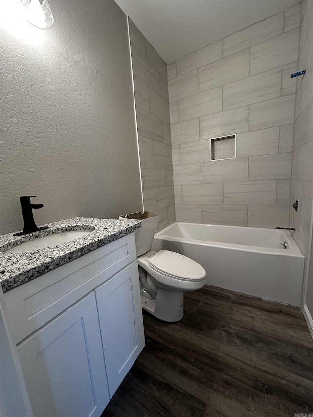 full bathroom featuring vanity, tiled shower / bath combo, wood-type flooring, and toilet