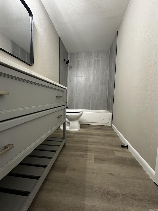 bathroom with hardwood / wood-style flooring, tiled shower / bath combo, and toilet