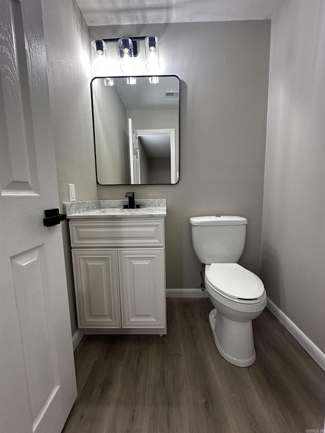 bathroom featuring vanity, hardwood / wood-style flooring, and toilet