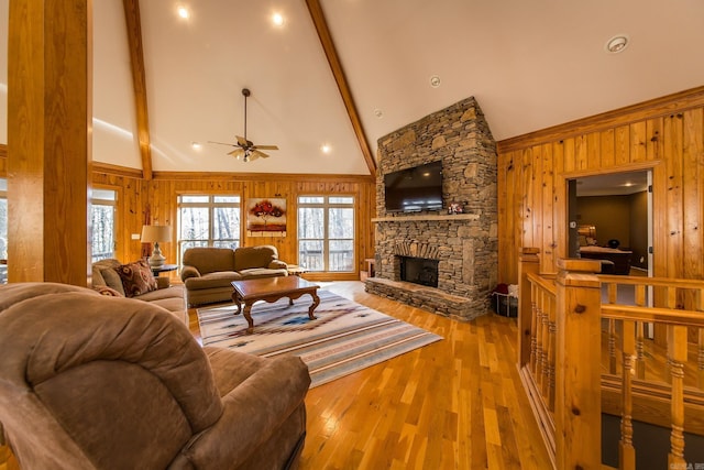 living room with light wood-type flooring, ceiling fan, beam ceiling, high vaulted ceiling, and a fireplace