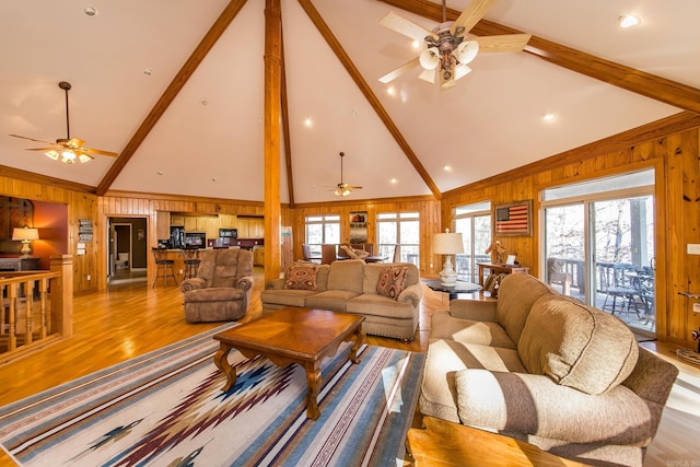 living room featuring beam ceiling, light hardwood / wood-style floors, and high vaulted ceiling