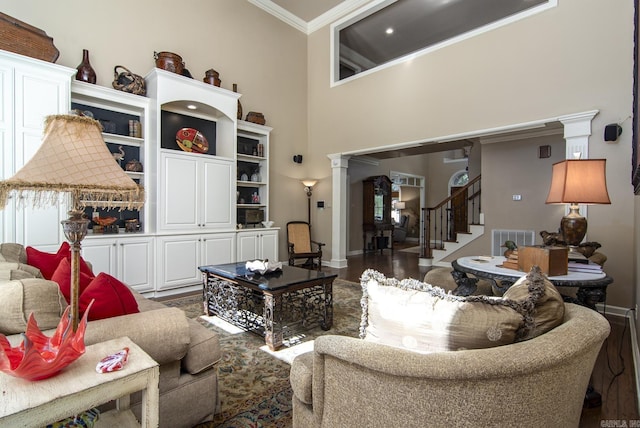 living room with a high ceiling, dark hardwood / wood-style floors, ornate columns, and crown molding