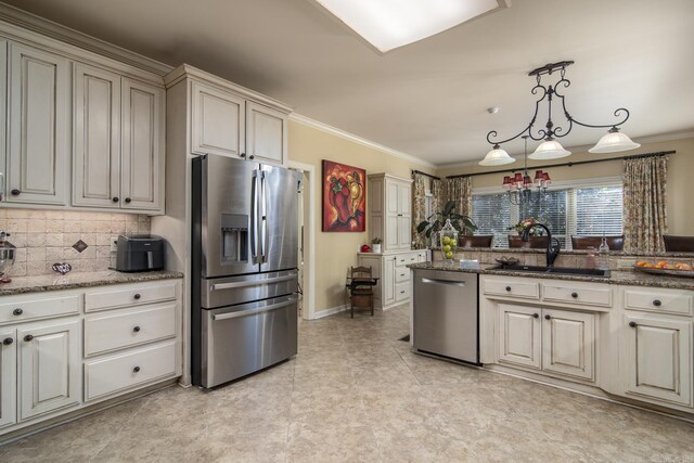 kitchen featuring sink, dark stone counters, pendant lighting, cream cabinetry, and appliances with stainless steel finishes