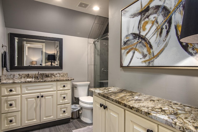 bathroom featuring vanity, toilet, a shower, and vaulted ceiling