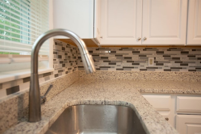 details with white cabinets, light stone counters, and backsplash