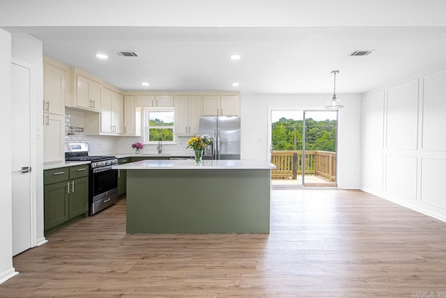 kitchen featuring appliances with stainless steel finishes, sink, pendant lighting, light hardwood / wood-style flooring, and a center island