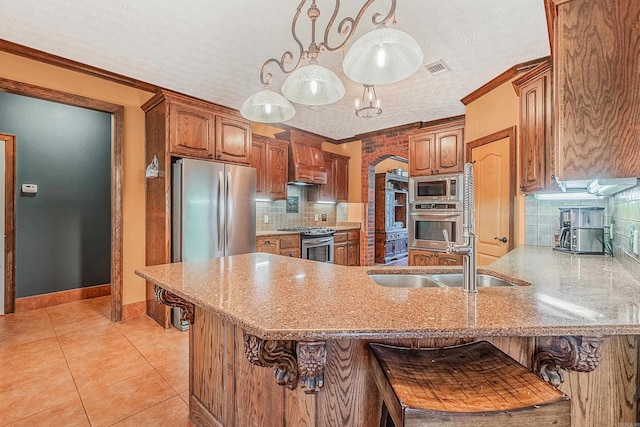 kitchen with sink, a textured ceiling, tasteful backsplash, a kitchen bar, and stainless steel appliances