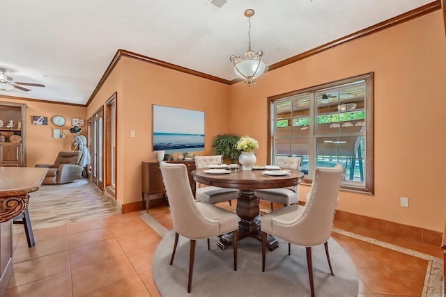 tiled dining room with ceiling fan and crown molding