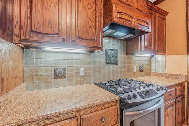 kitchen featuring decorative backsplash, light stone countertops, and stainless steel range with gas stovetop