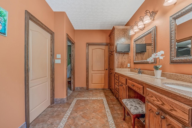 bathroom with tile patterned flooring, a textured ceiling, and vanity