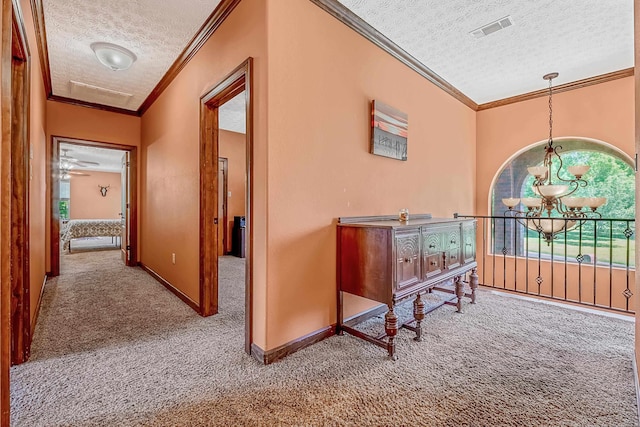 hallway with crown molding, carpet floors, a textured ceiling, and an inviting chandelier