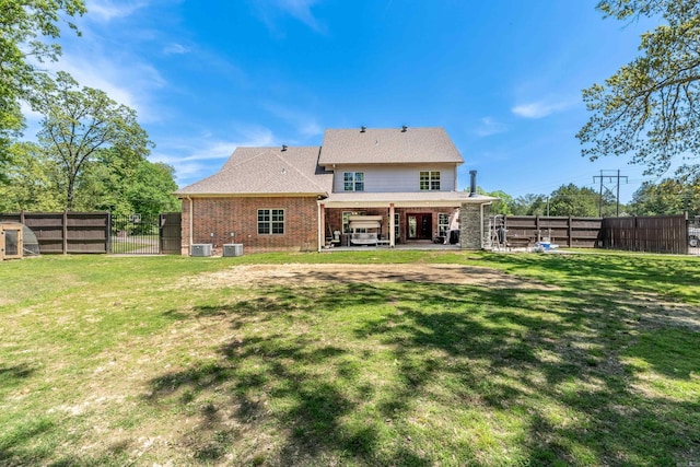 back of property with a lawn, central air condition unit, and a patio