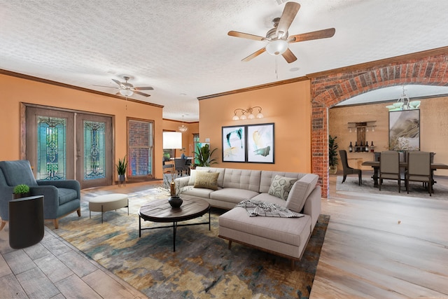 living room with a textured ceiling, ceiling fan with notable chandelier, and ornamental molding