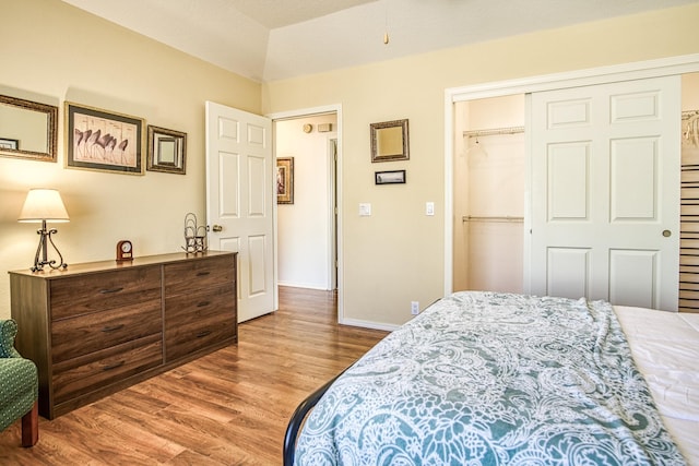 bedroom featuring a closet, wood-type flooring, and lofted ceiling