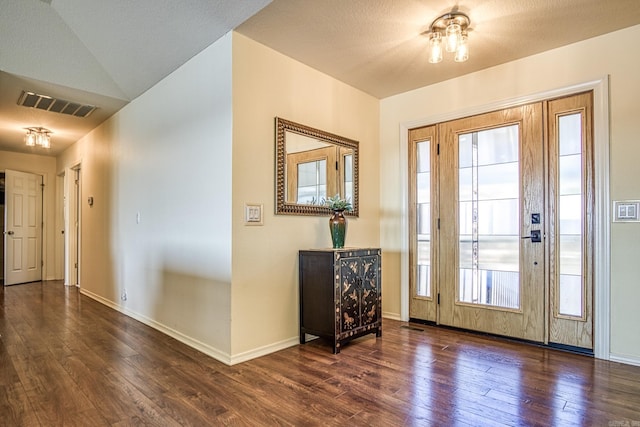 foyer entrance with plenty of natural light, lofted ceiling, and dark wood-type flooring