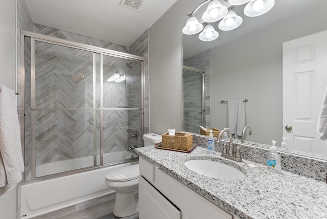 full bathroom featuring vanity, combined bath / shower with glass door, and toilet