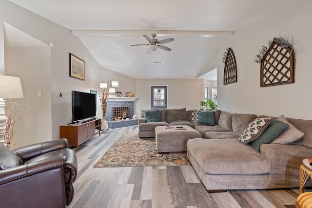 living room featuring light hardwood / wood-style flooring, a fireplace, lofted ceiling with beams, and ceiling fan