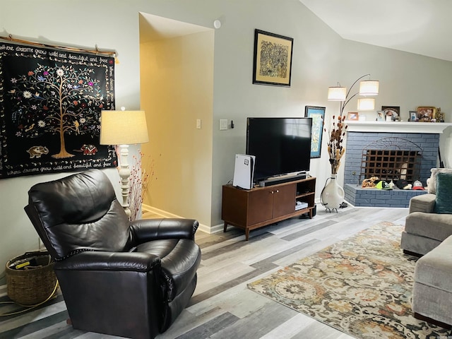 living room featuring lofted ceiling, a fireplace, and light hardwood / wood-style flooring