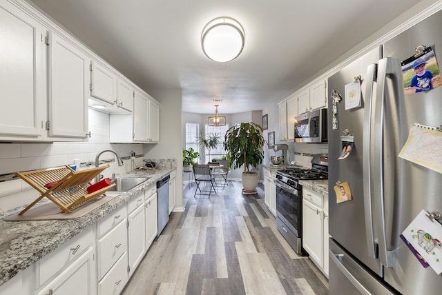 kitchen featuring sink, appliances with stainless steel finishes, white cabinetry, hanging light fixtures, and tasteful backsplash