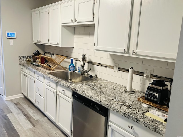 kitchen featuring sink, white cabinets, stainless steel dishwasher, light hardwood / wood-style floors, and light stone countertops