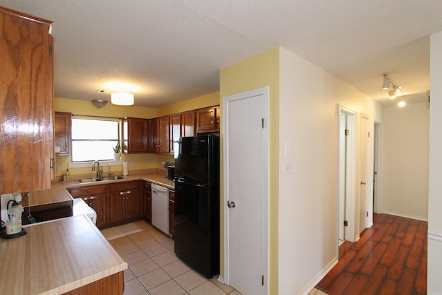 kitchen with black refrigerator, stove, sink, dishwasher, and light tile patterned flooring