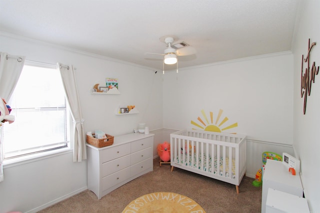 carpeted bedroom with ceiling fan, a crib, and ornamental molding