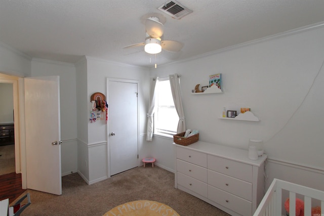 carpeted bedroom featuring a crib, ceiling fan, and crown molding