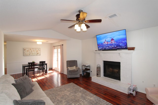 living room featuring ceiling fan, dark hardwood / wood-style flooring, lofted ceiling, and a brick fireplace