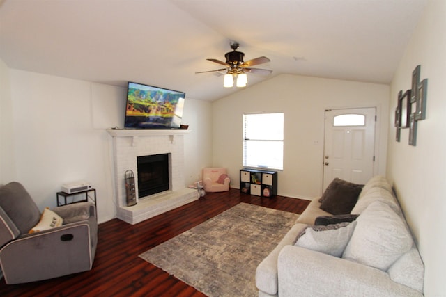 living room with ceiling fan, vaulted ceiling, a fireplace, and dark wood-type flooring