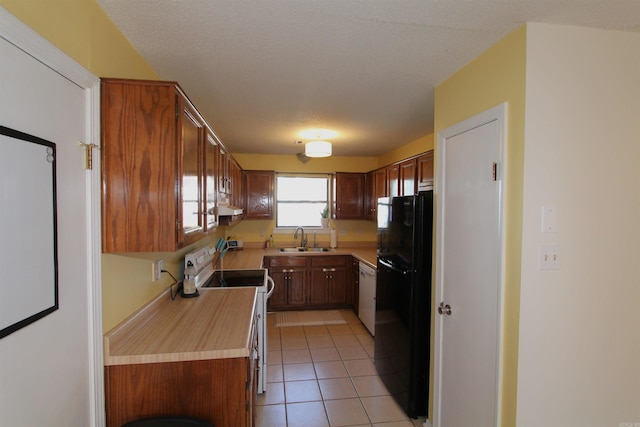 kitchen featuring stove, white dishwasher, black fridge, sink, and light tile patterned flooring