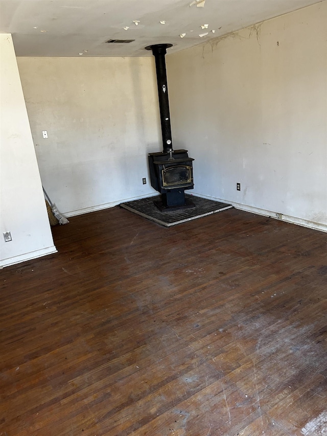 unfurnished living room featuring dark hardwood / wood-style floors and a wood stove