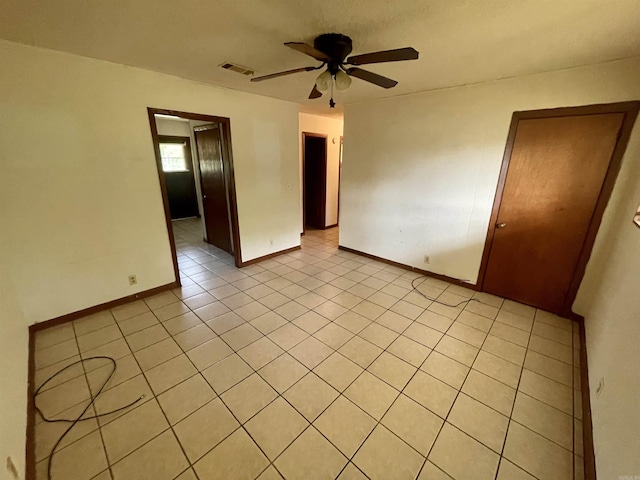 tiled spare room featuring ceiling fan