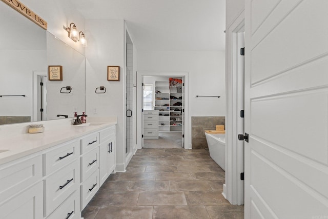 bathroom with vanity, shower with separate bathtub, and tile walls