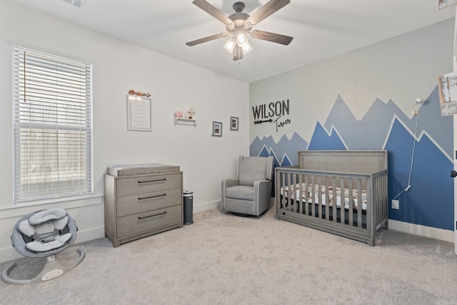 bedroom featuring ceiling fan, light colored carpet, and a crib