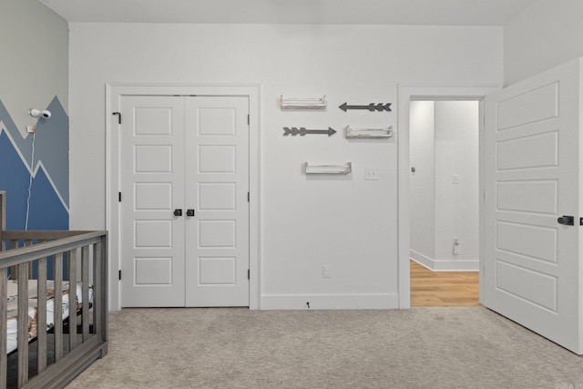 bedroom with light carpet, a nursery area, and a closet