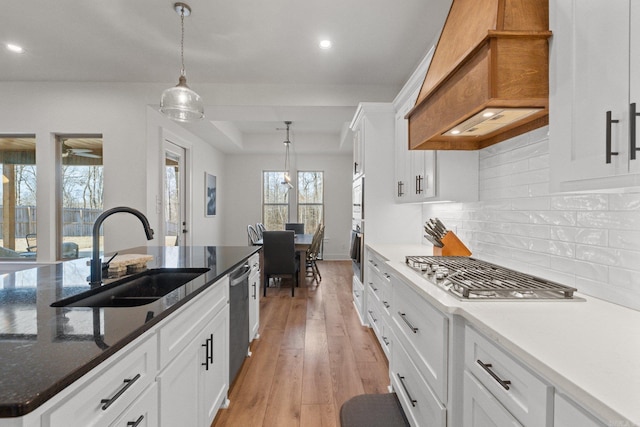 kitchen with premium range hood, white cabinetry, sink, and stainless steel appliances