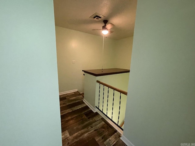 stairs featuring a textured ceiling, hardwood / wood-style flooring, and ceiling fan