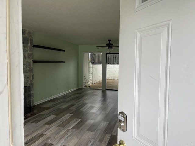 unfurnished living room featuring dark hardwood / wood-style floors, ceiling fan, and a fireplace