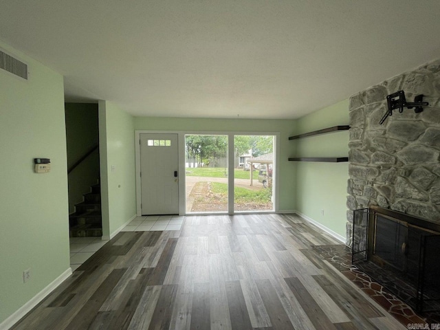 unfurnished living room featuring hardwood / wood-style floors and a stone fireplace