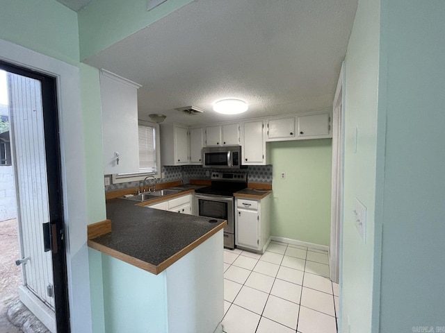 kitchen featuring sink, tasteful backsplash, kitchen peninsula, white cabinets, and appliances with stainless steel finishes