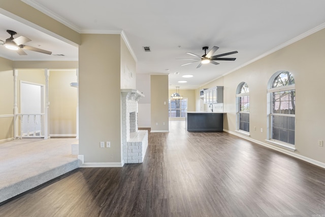 unfurnished living room featuring ceiling fan, sink, a brick fireplace, dark hardwood / wood-style floors, and ornamental molding