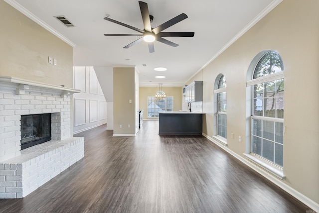 unfurnished living room featuring plenty of natural light, ornamental molding, and ceiling fan with notable chandelier