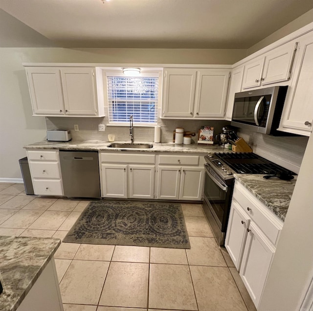 kitchen featuring stainless steel appliances, light tile patterned flooring, white cabinetry, and sink