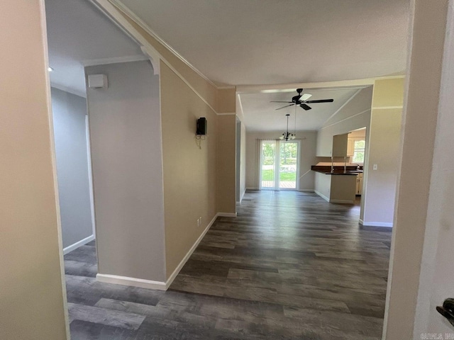 corridor featuring dark hardwood / wood-style flooring, ornamental molding, and vaulted ceiling