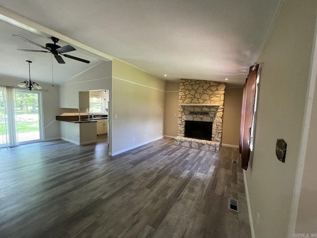 unfurnished living room with a textured ceiling, vaulted ceiling, ceiling fan, dark hardwood / wood-style floors, and a stone fireplace