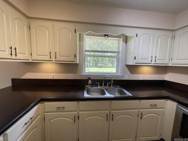 kitchen with a textured ceiling, white cabinetry, sink, and range