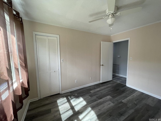 unfurnished bedroom with a closet, crown molding, ceiling fan, and dark wood-type flooring