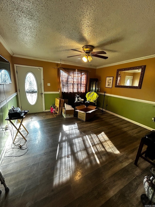 living room with a textured ceiling, ceiling fan, ornamental molding, and dark wood-type flooring