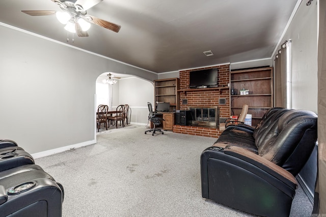 carpeted living room with ceiling fan, ornamental molding, and a fireplace